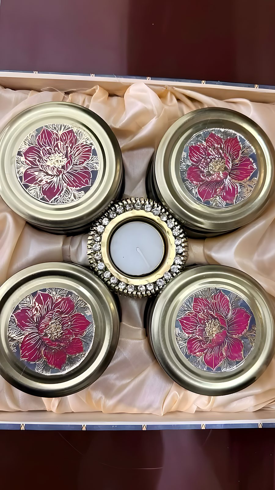 Four floral-lidded jars and a tealight arranged in a satin-lined hamper
